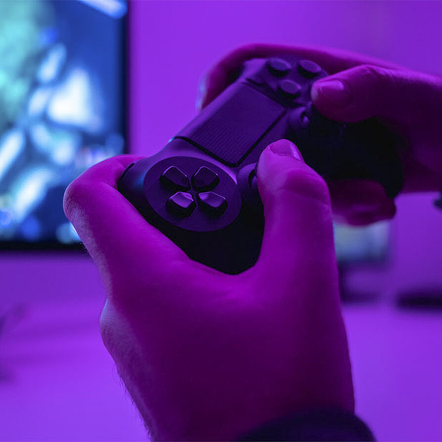 Closeup hands of anonymous male holding modern controller while playing video game in dark room